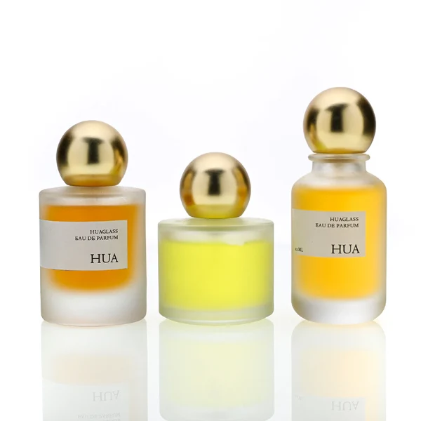 HUA0164 perfume bottle, cylindrical frosted glass body with 30 ml, 50 ml, or 100 ml liquid, spherical gold-colored plastic cap, outer label with printed logo, modern elegant design, ideal for gifting and daily use.