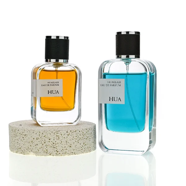 HUA0165 perfume bottle, rectangular transparent glass body with 30 ml, 50 ml, or 100 ml liquid, cylindrical plastic cap wrapped in leather with gold metallic neck, outer label with printed logo, modern elegant design, ideal for gifting and daily use.