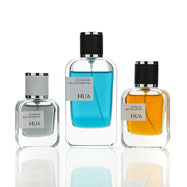 HUA0165 perfume bottle, rectangular transparent glass body with 30 ml, 50 ml, or 100 ml liquid, cylindrical plastic cap wrapped in leather with gold metallic neck, outer label with printed logo, modern elegant design, ideal for gifting and daily use.