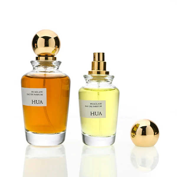 HUA0167 perfume bottle, kettle-shaped cylindrical transparent glass body with 50 ml or 100 ml liquid, spherical glossy plastic cap with gold neck, outer label with printed logo, modern elegant design, ideal for gifting and daily use.