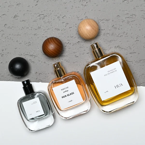 HUA0168 perfume bottle, rectangular transparent glass body with 30 ml, 50 ml, or 100 ml liquid, spherical wooden cap, outer label with printed logo, modern natural elegant design, ideal for gifting and daily use.