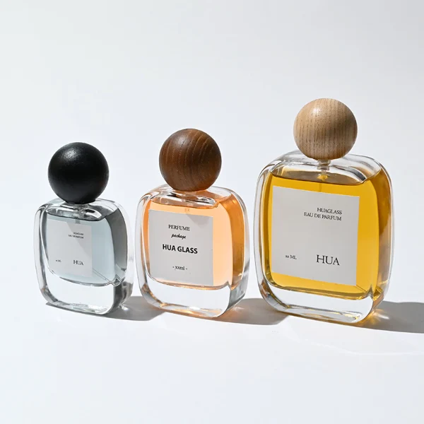 HUA0168 perfume bottle, rectangular transparent glass body with 30 ml, 50 ml, or 100 ml liquid, spherical wooden cap, outer label with printed logo, modern natural elegant design, ideal for gifting and daily use.