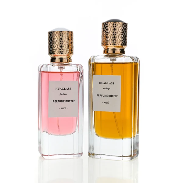 HUA0170 perfume bottle, rectangular transparent glass body with 50 ml or 80 ml liquid, cylindrical plastic cap with engraved decorative pattern and gold neck ring, outer label with printed logo, modern luxurious design, ideal for gifting and daily use.