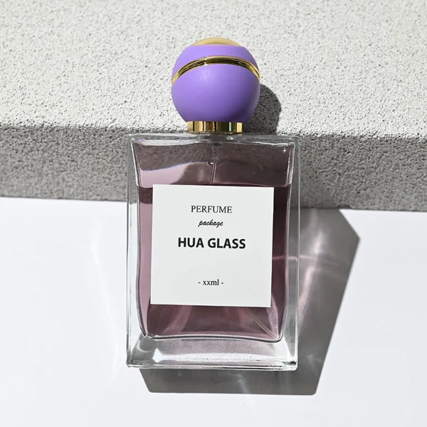 HUA0171 perfume bottle, rectangular transparent glass body with 30 ml, 50 ml, or 100 ml liquid, spherical plastic cap with diagonal gold stripe detailing and gold neck ring, outer label with printed logo, modern elegant design, ideal for gifting and daily use.