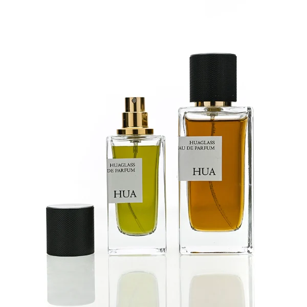 HUA0172 perfume bottle, rectangular transparent glass body with 30 ml, 50 ml, or 100 ml liquid, smooth black cylindrical plastic cap with gold sprayer and gold neck ring, outer label with printed logo, modern minimalist design, ideal for gifting and daily use.