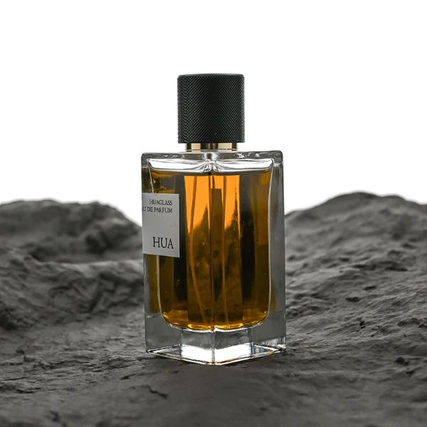 HUA0172 perfume bottle, rectangular transparent glass body with 30 ml, 50 ml, or 100 ml liquid, smooth black cylindrical plastic cap with gold sprayer and gold neck ring, outer label with printed logo, modern minimalist design, ideal for gifting and daily use.