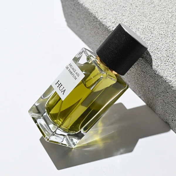 HUA0172 perfume bottle, rectangular transparent glass body with 30 ml, 50 ml, or 100 ml liquid, smooth black cylindrical plastic cap with gold sprayer and gold neck ring, outer label with printed logo, modern minimalist design, ideal for gifting and daily use.