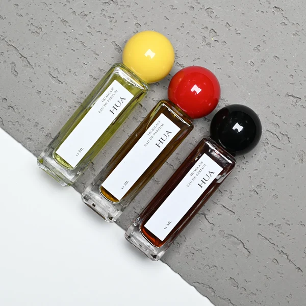 HUA0177 perfume bottle, slim rectangular transparent glass body with 30 ml, 50 ml, or 100 ml liquid, glossy spherical plastic cap with customizable colors, printed vertical logo label, modern minimalist elegant design, ideal for gifting and daily use.