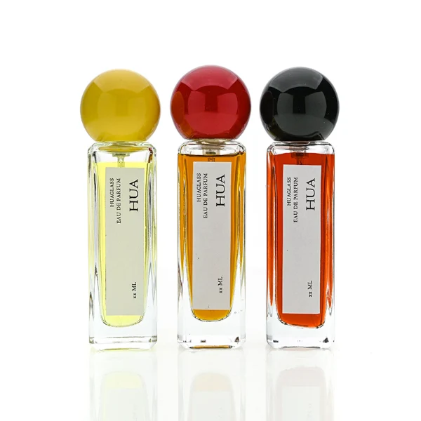 HUA0177 perfume bottle, slim rectangular transparent glass body with 30 ml, 50 ml, or 100 ml liquid, glossy spherical plastic cap with customizable colors, printed vertical logo label, modern minimalist elegant design, ideal for gifting and daily use.