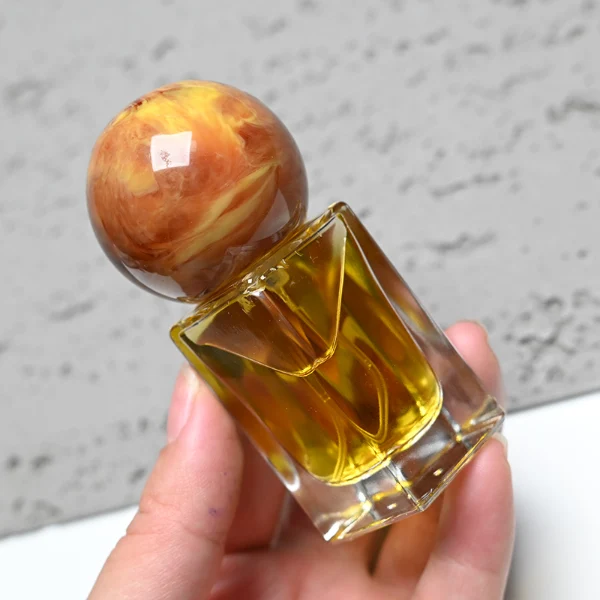 HUA0181 perfume bottle, rectangular faceted transparent glass body with 15 ml, 30 ml, 50 ml, or 100 ml liquid, glossy spherical resin cap with marble-inspired texture and customizable colors, printed logo label, modern artistic luxury design, ideal for gifting and daily use.