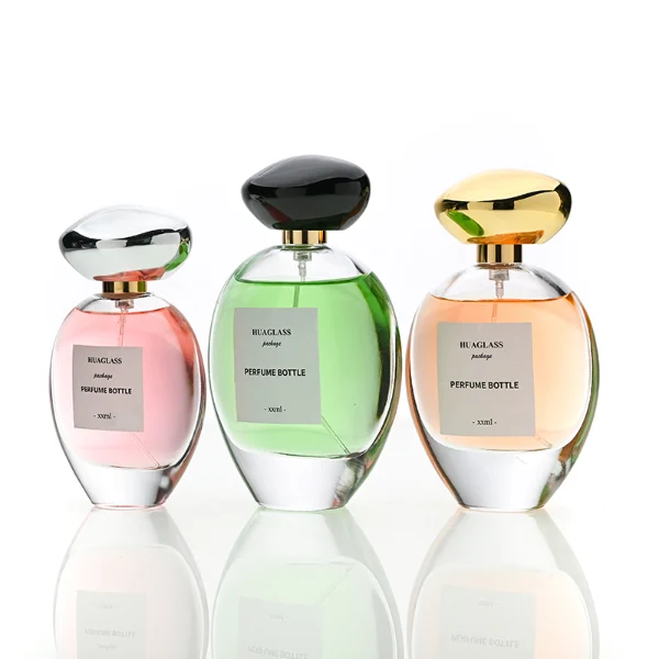 HUA0182 perfume bottle, oval transparent glass body with 30 ml, 50 ml, 75 ml, or 100 ml liquid, irregular oval-shaped glossy plastic cap with gold neck, printed logo label, modern elegant luxury design, ideal for gifting and daily use.