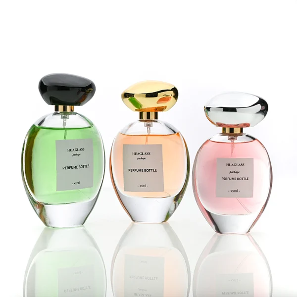 HUA0182 perfume bottle, oval transparent glass body with 30 ml, 50 ml, 75 ml, or 100 ml liquid, irregular oval-shaped glossy plastic cap with gold neck, printed logo label, modern elegant luxury design, ideal for gifting and daily use.