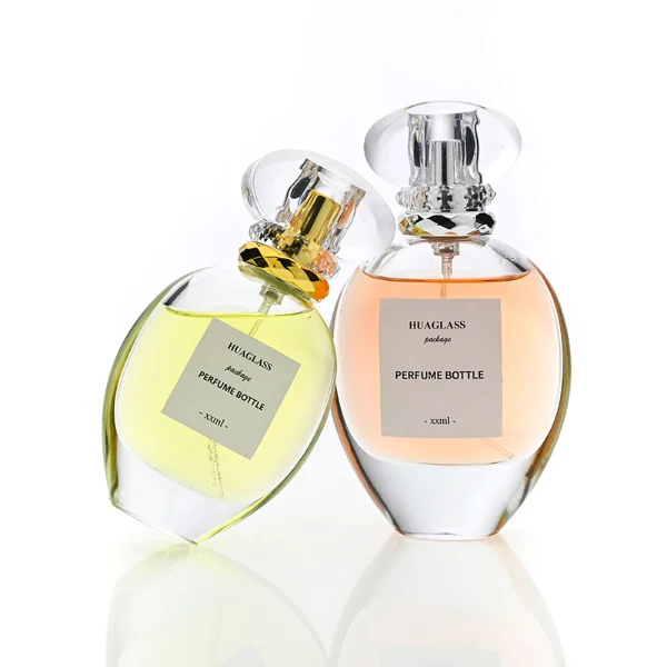 HUA0183 perfume bottle, oval transparent glass body with 30 ml, 50 ml, 75 ml, or 100 ml liquid, transparent disc-shaped plastic cap with layered decorative neck detail, printed logo label, modern elegant luxury design, ideal for gifting and daily use.