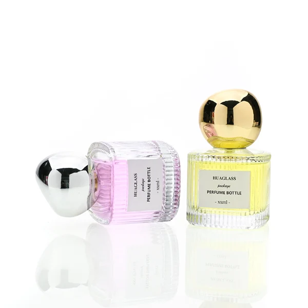 HUA0184 perfume bottle, cylindrical ribbed transparent glass body with 50 ml or 100 ml liquid, irregular glossy spherical plastic cap with customizable colors, printed logo label, modern artistic luxury design, ideal for gifting and daily use.