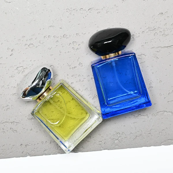 HUA0185 perfume bottle, trapezoidal transparent glass body with 50 ml or 100 ml liquid, irregular oval-shaped glossy plastic cap with customizable colors and gold neck, printed glass logo, modern fashionable luxury design, ideal for gifting and daily use.