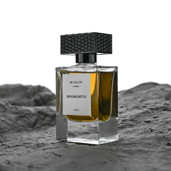 HUA0189 perfume bottle, rectangular transparent glass body with 50 ml liquid, rectangular textured plastic cap with customizable color matching the neck, printed logo label, modern premium luxury design, ideal for gifting and daily use.