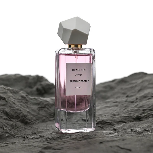 HUA0192 perfume bottle, rectangular transparent glass body with 50 ml or 80 ml liquid, irregular faceted geometric plastic cap with gold neck, printed logo label, modern artistic luxury design, ideal for gifting and daily use.