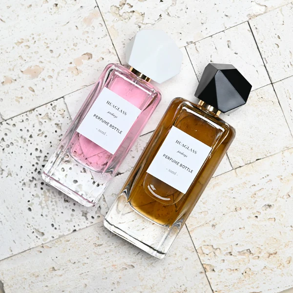 HUA0192 perfume bottle, rectangular transparent glass body with 50 ml or 80 ml liquid, irregular faceted geometric plastic cap with gold neck, printed logo label, modern artistic luxury design, ideal for gifting and daily use.