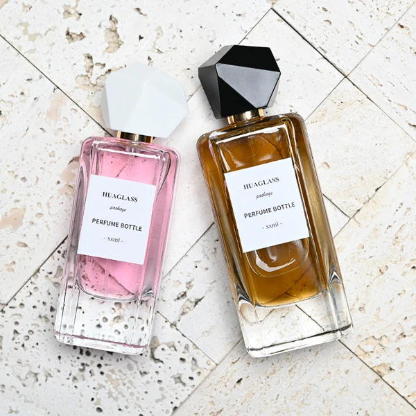 HUA0192 perfume bottle, rectangular transparent glass body with 50 ml or 80 ml liquid, irregular faceted geometric plastic cap with gold neck, printed logo label, modern artistic luxury design, ideal for gifting and daily use.