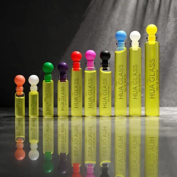 HUA0198 perfume bottle, slim cylindrical transparent glass body with 0.5 ml, 1 ml, 1.5 ml, 2 ml, 3 ml, or 5 ml liquid, black or white protective spherical plastic cap, Corrugated Plastic closure, printed logo, compact and practical design, ideal for travel and sample use.