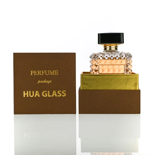 HUA0201 perfume bottle, square crystal-cut high-transparency glass body with thick base, 50 ml or 100 ml liquid, cylindrical black plastic cap with gold neck ring, brand label applied on the surface, modern luxurious design, ideal for gifting and daily use.