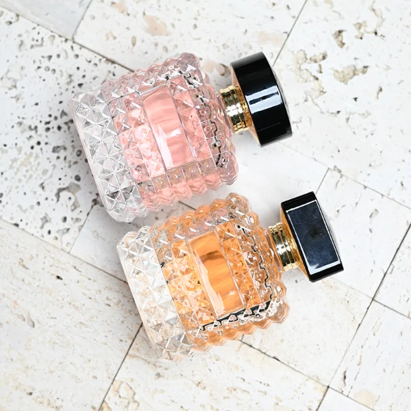 HUA0201 perfume bottle, square crystal-cut high-transparency glass body with thick base, 50 ml or 100 ml liquid, cylindrical black plastic cap with gold neck ring, brand label applied on the surface, modern luxurious design, ideal for gifting and daily use.