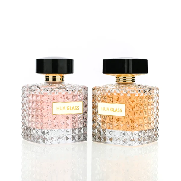 HUA0201 perfume bottle, square crystal-cut high-transparency glass body with thick base, 50 ml or 100 ml liquid, cylindrical black plastic cap with gold neck ring, brand label applied on the surface, modern luxurious design, ideal for gifting and daily use.