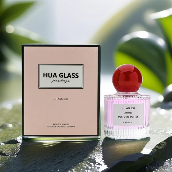 HUA0203 perfume bottle, cylindrical ribbed transparent glass body with thick base, 50 ml or 100 ml liquid, spherical glossy plastic cap in red or yellow, brand label applied on the surface, modern luxurious design, ideal for gifting and daily use.