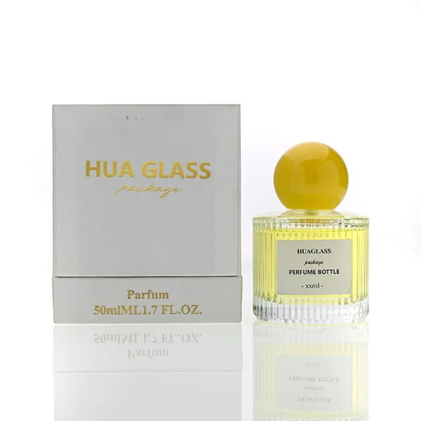 HUA0203 perfume bottle, cylindrical ribbed transparent glass body with thick base, 50 ml or 100 ml liquid, spherical glossy plastic cap in red or yellow, brand label applied on the surface, modern luxurious design, ideal for gifting and daily use.