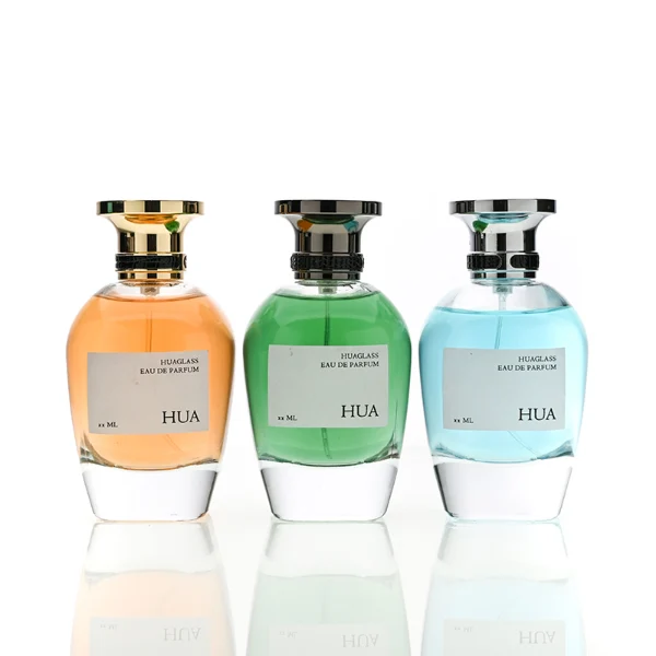 HUA0204 perfume bottle, flattened rounded streamlined transparent glass body with thick base and high-gloss finish, 100 ml liquid, flat cylindrical Zamac cap with slightly enlarged flat top fitting snugly on the neck, printed logo label, modern luxurious design, ideal for gifting and daily use.