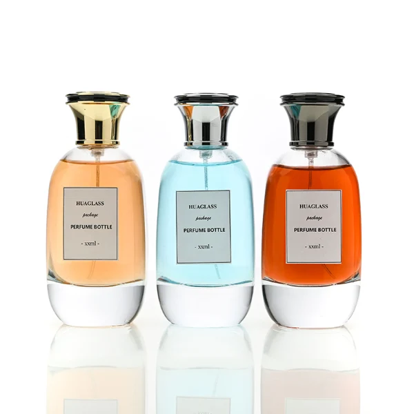HUA0205 perfume bottle, flattened rounded streamlined transparent glass body with thick base and high-gloss finish, 100 ml liquid, flat cylindrical Zamac cap in black, gold, or silver with slightly enlarged flat top fitting snugly on the neck, brand label applied on the surface, modern luxurious design, ideal for gifting and daily use.