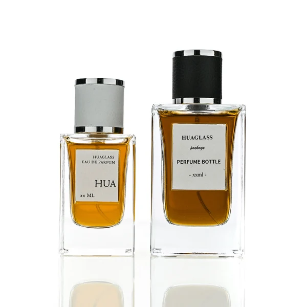 HUA0206 perfume bottle, rectangular transparent glass body with thick base, 50 ml or 100 ml liquid, cylindrical leather-wrapped cap with silver rings on both ends, brand label applied on the surface, modern masculine luxury design, ideal for gifting and daily use.