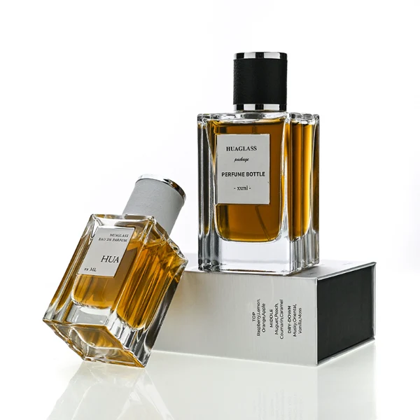 HUA0206 perfume bottle, rectangular transparent glass body with thick base, 50 ml or 100 ml liquid, cylindrical leather-wrapped cap with silver rings on both ends, brand label applied on the surface, modern masculine luxury design, ideal for gifting and daily use.