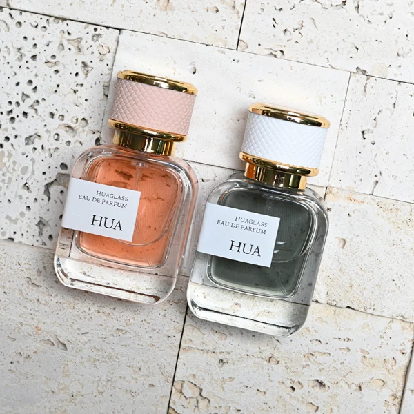 HUA0207 perfume bottle, rectangular transparent glass body with thick base, 30 ml, 50 ml, or 100 ml liquid, cylindrical leather-wrapped cap with customizable colors, brand label applied on the surface, modern luxurious design, ideal for gifting and daily use.