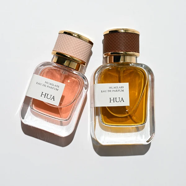 HUA0207 perfume bottle, rectangular transparent glass body with thick base, 30 ml, 50 ml, or 100 ml liquid, cylindrical leather-wrapped cap with customizable colors, brand label applied on the surface, modern luxurious design, ideal for gifting and daily use.