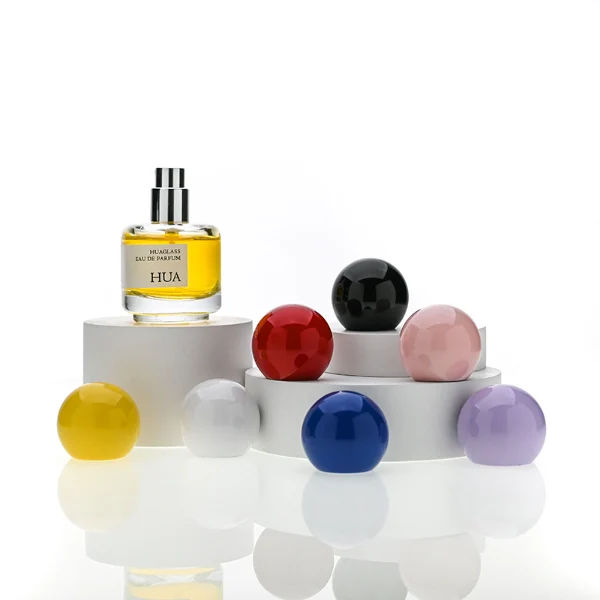 HUA0208 perfume bottle, cylindrical transparent glass body with thick base, 30 ml liquid, spherical plastic cap in blue, red, or yellow, brand label applied on the surface, modern playful luxury design, ideal for gifting and daily use.