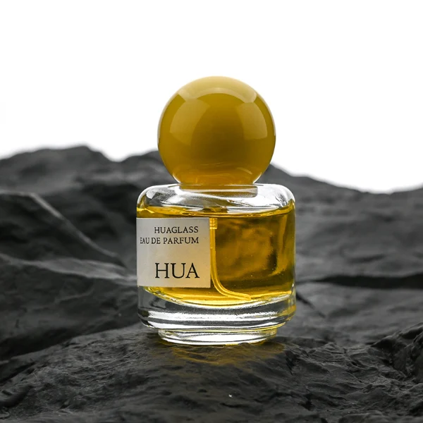 HUA0208 perfume bottle, cylindrical transparent glass body with thick base, 30 ml liquid, spherical plastic cap in blue, red, or yellow, brand label applied on the surface, modern playful luxury design, ideal for gifting and daily use.
