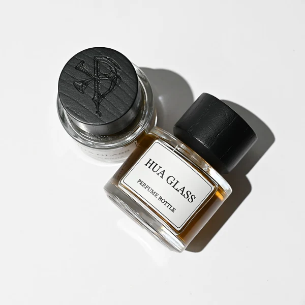 HUA0209 perfume bottle, cylindrical transparent glass body with thick base, 30 ml, 50 ml, or 100 ml liquid, cylindrical wooden cap with smooth matte finish, brand label applied on the surface, modern minimalist luxury design, ideal for gifting and daily use.