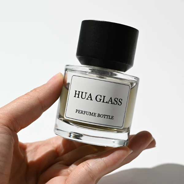 HUA0209 perfume bottle, cylindrical transparent glass body with thick base, 30 ml, 50 ml, or 100 ml liquid, cylindrical wooden cap with smooth matte finish, brand label applied on the surface, modern minimalist luxury design, ideal for gifting and daily use.