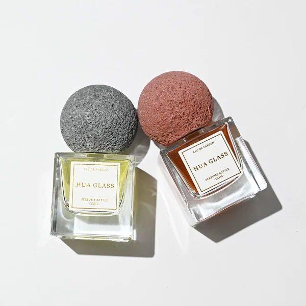 HUA0210 perfume bottle, square transparent glass body with thick base, 30 ml, 50 ml, or 100 ml liquid, spherical artificial stone cap with textured surface, brand label applied on the surface, modern artistic luxury design, ideal for gifting and daily use.