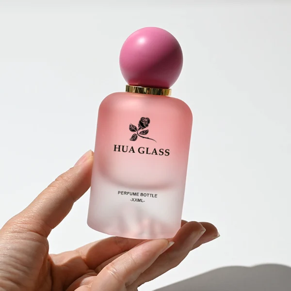 HUA0212 perfume bottle, rounded cylindrical frosted glass body with thick base, 30 ml, 50 ml, or 100 ml liquid, spherical plastic cap in customizable colors with gold neck ring, brand logo printed on the bottle, modern playful luxury design, ideal for gifting and daily use.