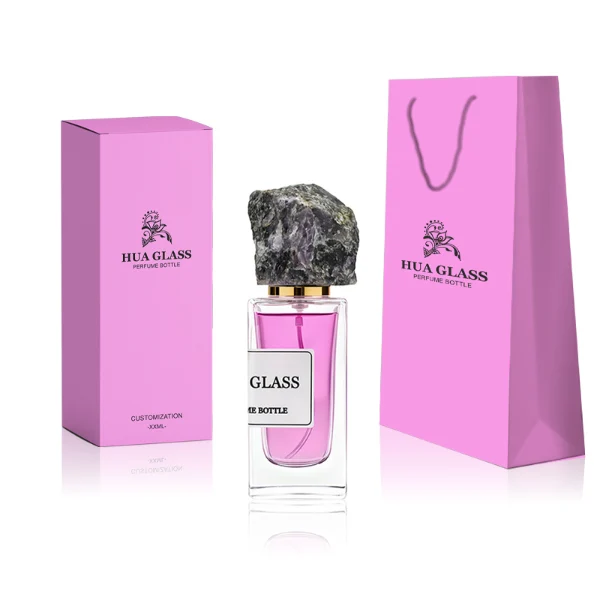 HUA0213 perfume bottle, rectangular transparent glass body with thick base, 30 ml, 50 ml, or 100 ml liquid, rough natural crystal stone cap with gold neck ring, brand label applied on the bottle surface, modern artistic luxury design, ideal for gifting and daily use.