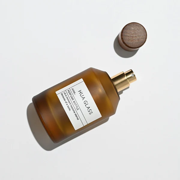HUA0214 perfume bottle, cylindrical frosted glass body with thick base, 30 ml, 50 ml, or 100 ml liquid, removable cylindrical wooden cap with spray nozzle, brand label applied on the surface, modern minimalist luxury design, ideal for gifting and daily use.