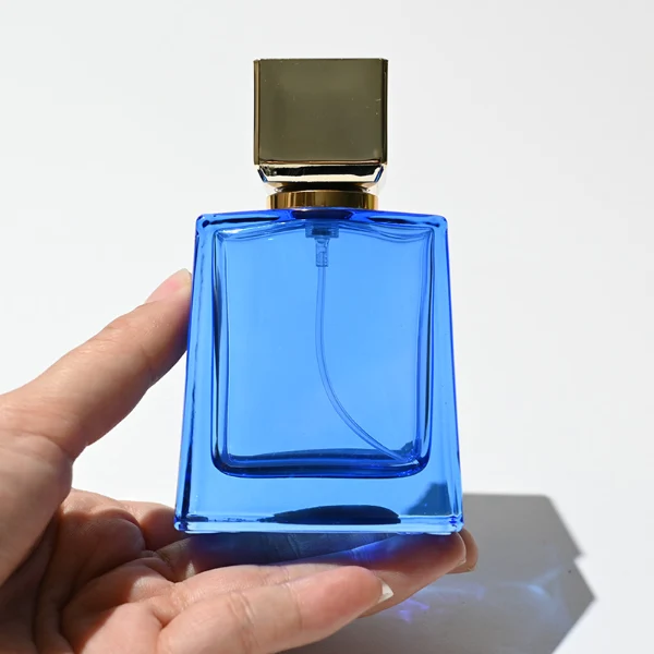HUA0215 perfume bottle, square transparent glass body with thick base, 50 ml or 100 ml liquid, square plastic cap with customizable metallic finish, printed brand logo, modern minimalist luxury design, ideal for gifting and daily use.