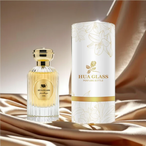 HUA0216 perfume bottle, ribbed transparent glass body with thick base, 50 ml or 100 ml liquid, cylindrical plastic cap with wave-shaped or slightly domed top with decorative grooves, metallic finish, gold logo label applied on bottle, modern luxurious fashion design, ideal for gifting and daily use.