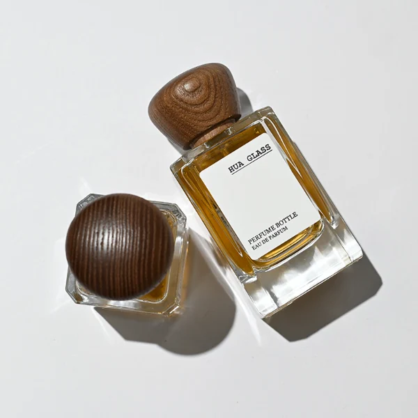 HUA0217 perfume bottle, square transparent glass body with thick base, 30 ml, 50 ml, or 100 ml liquid, rounded wooden cap, brand label applied on bottle, modern luxurious fashion design, ideal for gifting and daily use.