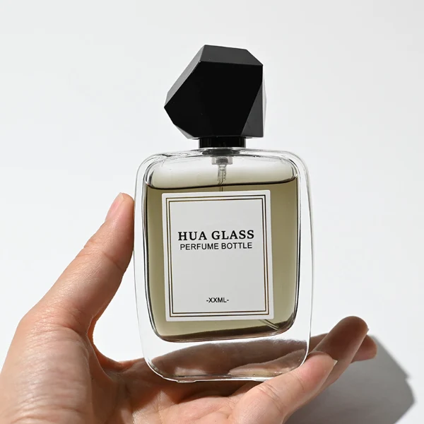 HUA0218 perfume bottle, rounded square transparent glass body with thick base, 30 ml, 50 ml, or 100 ml liquid, geometric multi-faceted plastic cap in black or white, brand label applied on bottle, modern luxurious fashion design, ideal for gifting and daily use.