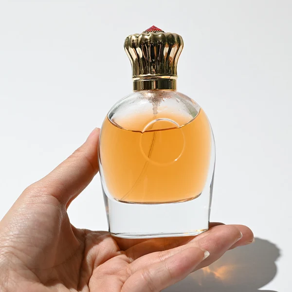 HUA0220 perfume bottle, rounded transparent glass body with thick base, 80 ml liquid, decorative Zamac cap with flat cylindrical top or petal-shaped dome top, brand label applied on bottle, modern luxurious fashion design, ideal for gifting and daily use.