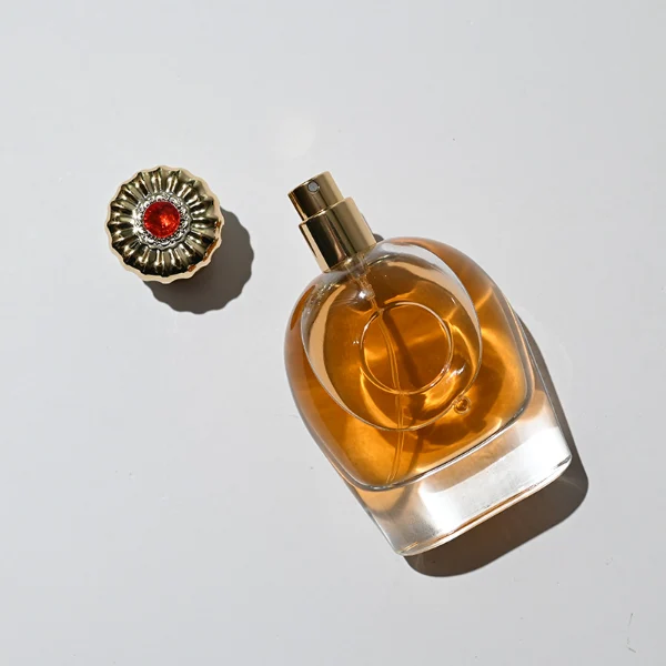 HUA0220 perfume bottle, rounded transparent glass body with thick base, 80 ml liquid, decorative Zamac cap with flat cylindrical top or petal-shaped dome top, brand label applied on bottle, modern luxurious fashion design, ideal for gifting and daily use.