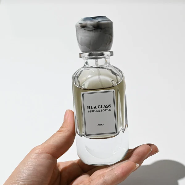 HUA0222 perfume bottle, rounded rectangular transparent glass body with thick base, 80 ml liquid, faceted resin cap with natural marbled pattern and customizable color, brand label applied on bottle, modern luxurious fashion design, ideal for gifting and daily use.